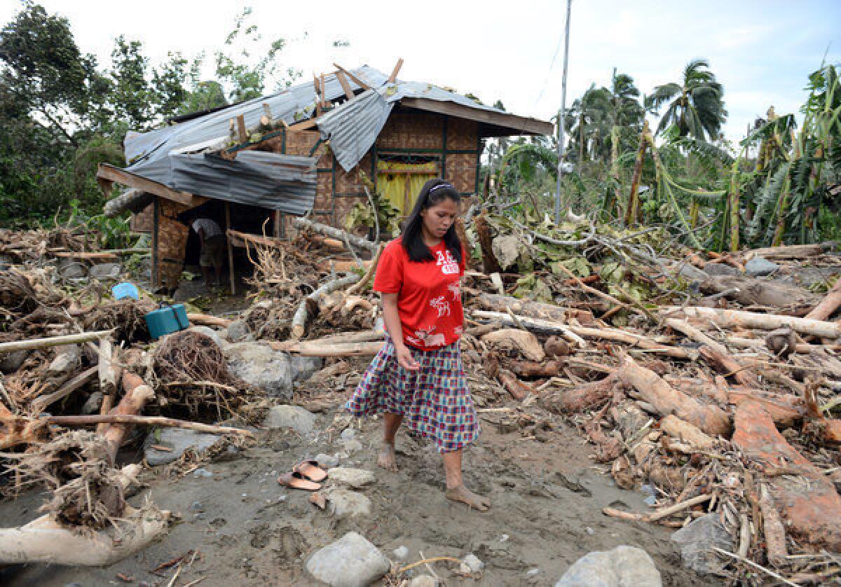 A woman walks amongst debris next to her damaged house in the village of Andap, New Bataan town, Compostela Valley province on Wednesday, a day after Typhoon Bopha hit the province.