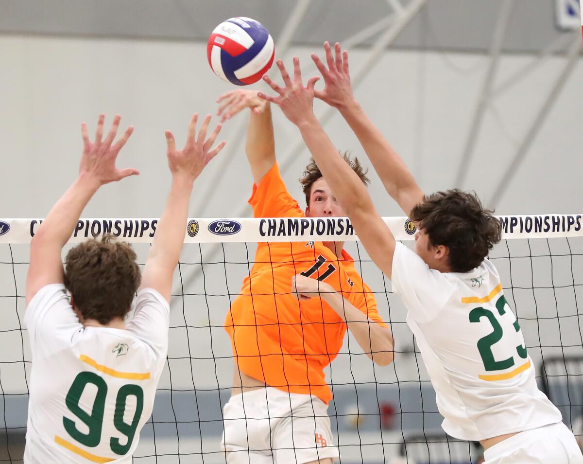 Huntington Beach's Logan Hutnick puts a kill between the blocks from Mira Costa.