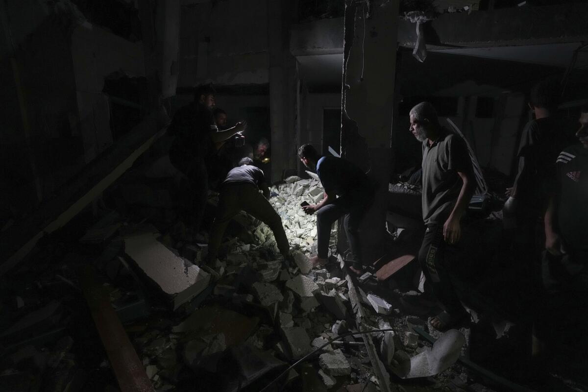 People search through rubble in the dark.