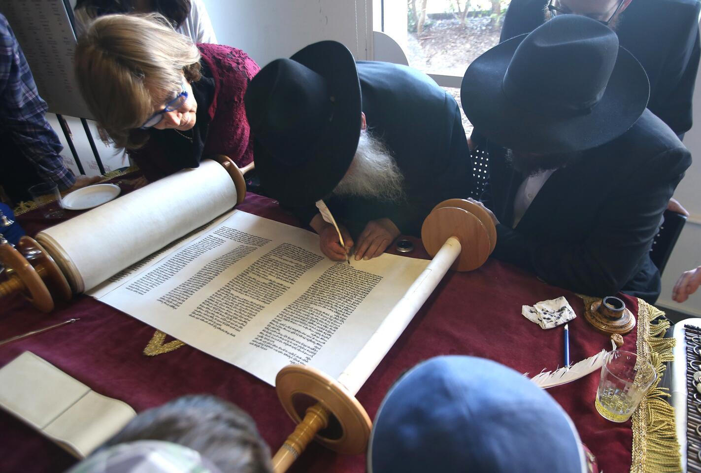 Special guest Leibel Groner of New York writes the final letters on UC Irvine's Unity Torah during a ceremony Monday at the university's Cross Cultural Center. Groner is the grandfather of Zevi Tenenbaum, the campus rabbi. The Torah will be placed at the Rohr Chabad at UCI.
