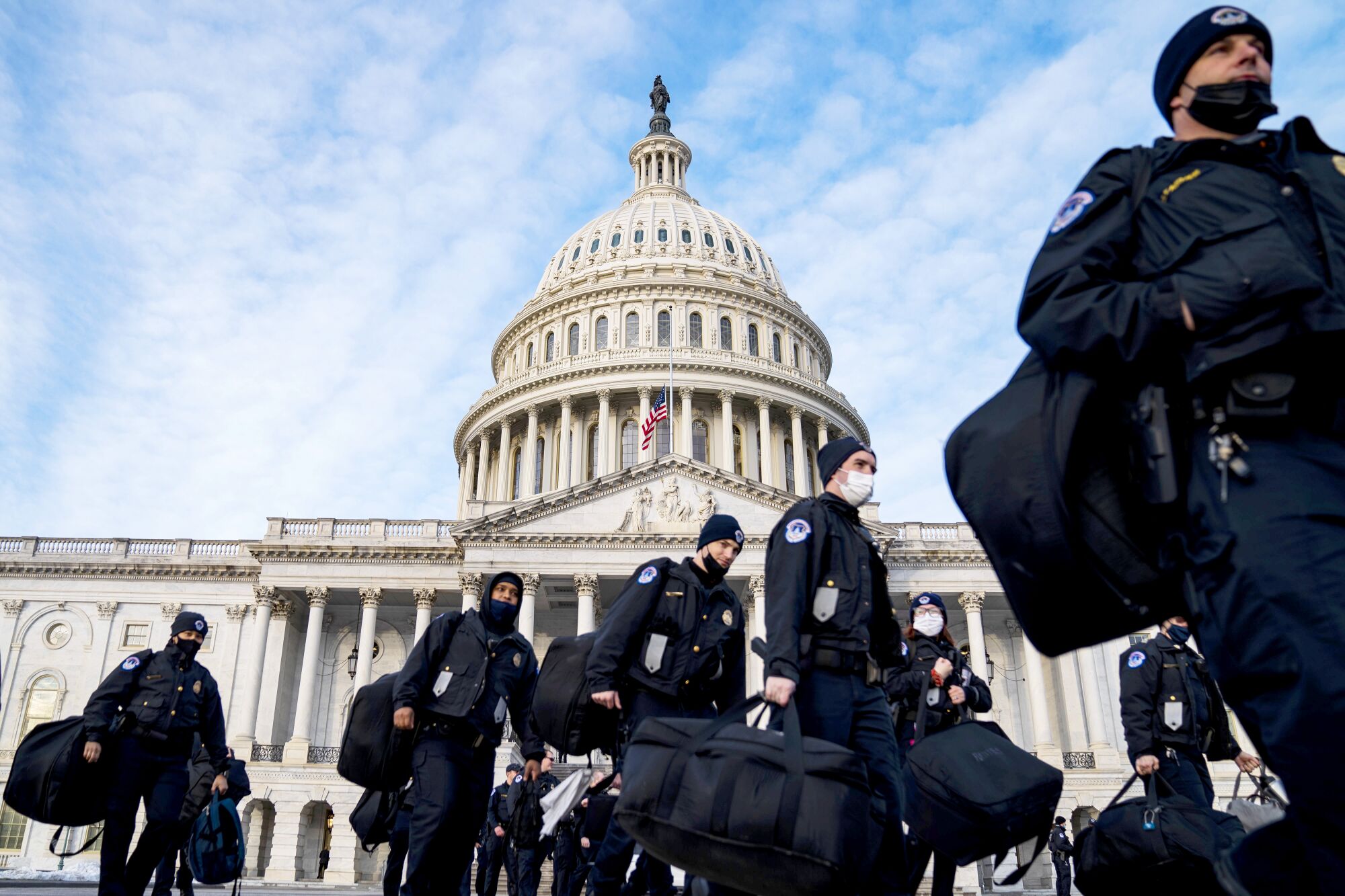 Capitol Police officers walk carrying duffle bags outside the Capitol 
