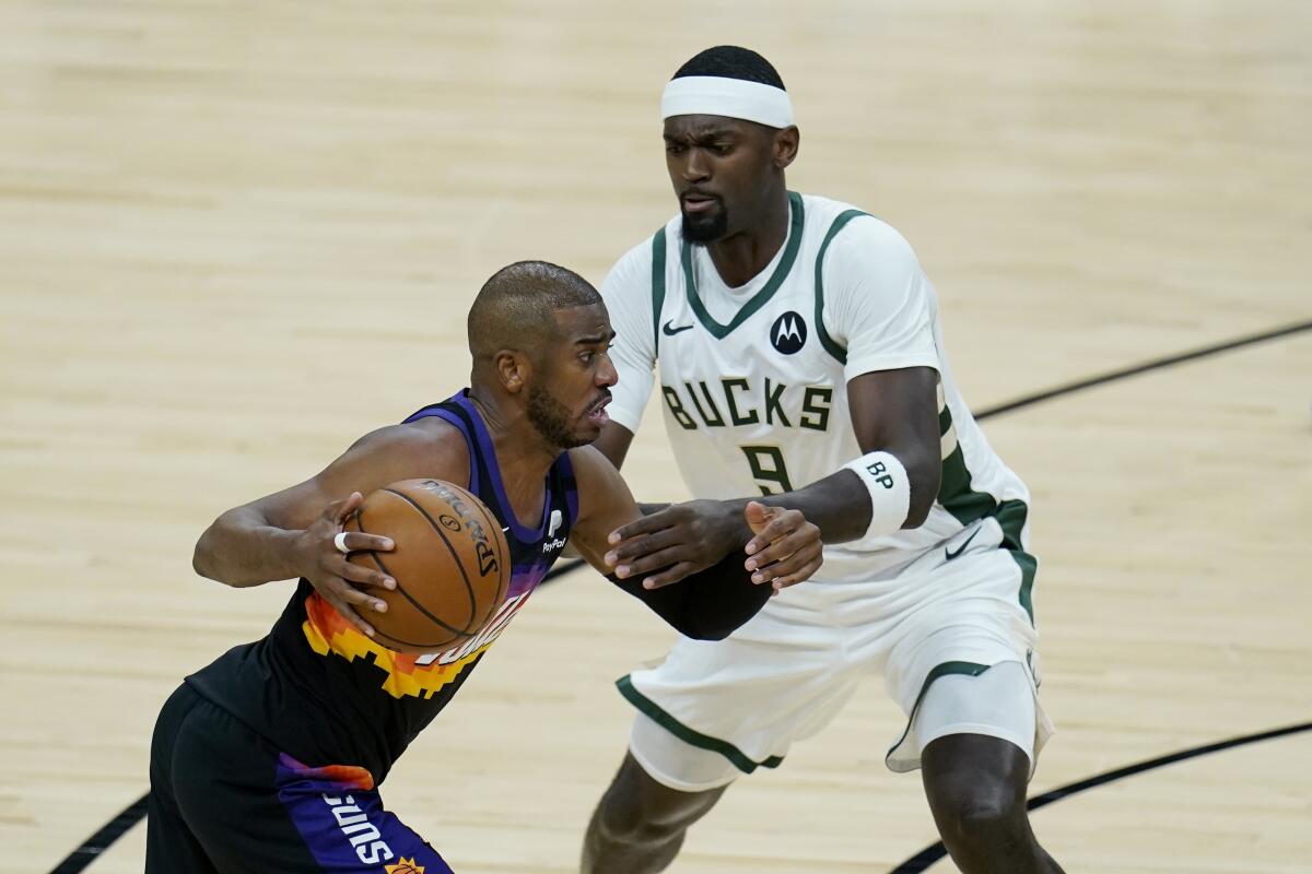 Phoenix Suns guard Chris Paul, left, dribbles the ball against Milwaukee Bucks center Bobby Portis (9) 