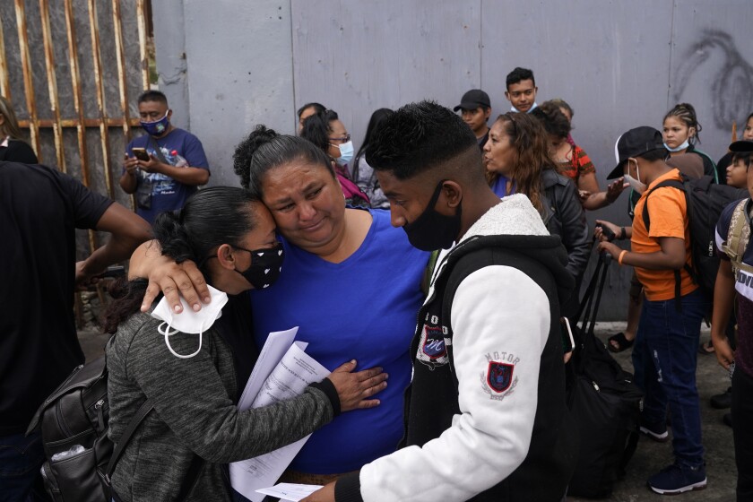 Lizeth Morales, left, of Honduras, and her son, Alex Cortillo, right, get a hug from Erika Valladares Ponce, center, as they wait to cross into the United States to begin the asylum process Monday, July 5, 2021, in Tijuana, Mexico. Dozens of people are allowed into the U.S. twice a day at a San Diego border crossing, part of a system that the Biden administration cobbled together to start opening back up the asylum system in the U.S. Immigration advocates have been tasked with choosing which migrants can apply for a limited number of slots to claim humanitarian protection. (AP Photo/Gregory Bull)