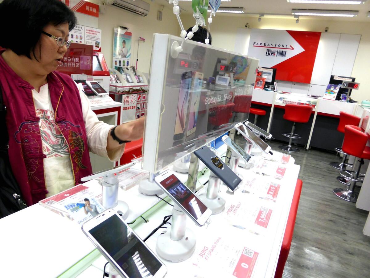 A woman selects cellphones in an cell phone shop in Taipei, Taiwan.