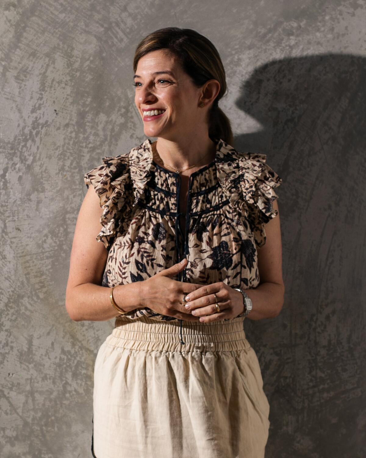 Chef Pati Jinich smiles in front of a gray wall.  