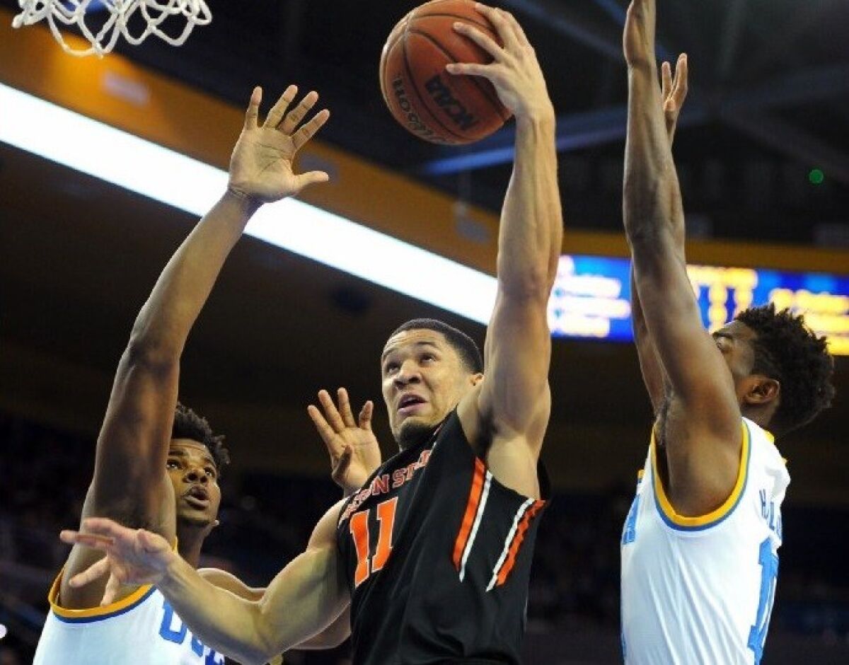 Oregon State guard Malcolm Duvivier goes to the hoop against UCLA forward Tony Parker, left, and guard Isaac Hamilton during a game on March 5 at Pauley Pavilion.