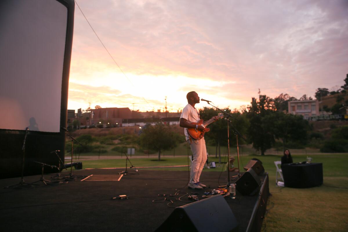 A man stands onstage singing and playing guitar at River Fest in L.A. State Historic Park