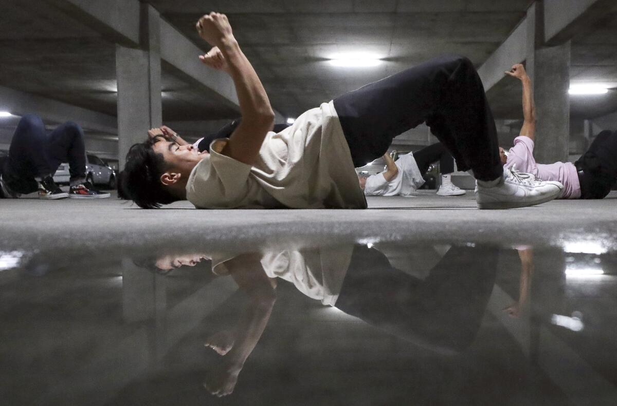 Joshua Candelria, 19, is reflected in a water puddle as he and other members of a hip-hop dance group perform during the end of the year choreography project put on by the SDSU Vietnamese Student Organization Modern, a collegiate hip-hop dance troupe, in a parking garage on the SDSU campus on Thursday, December 5, 2019 in San Diego, California.