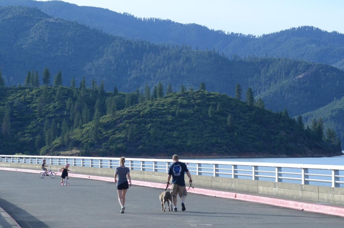 A family strolls atop Shasta Dam, north of Redding, Calif. (Christopher Reynolds/Los Angeles Times)