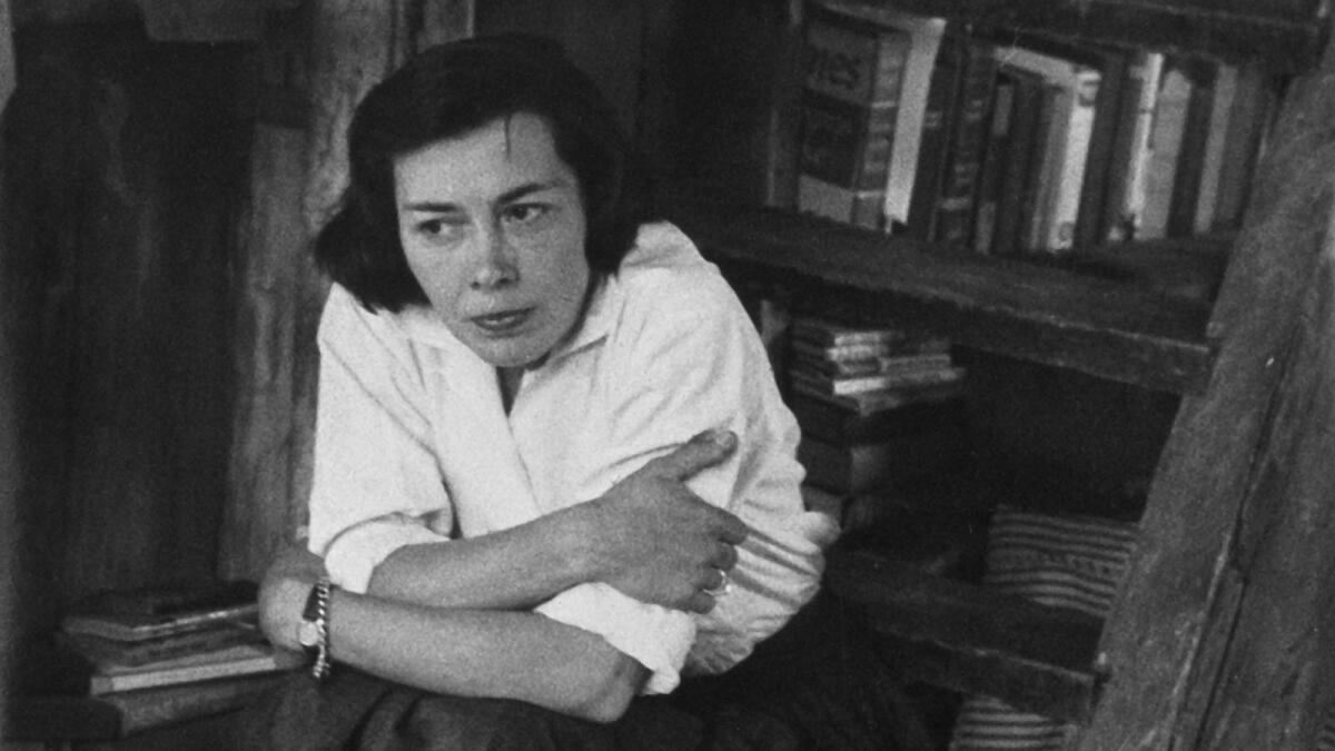 A woman in front of a bookcase.