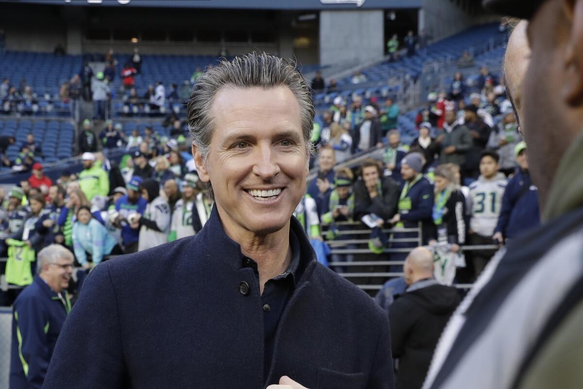 Gov. Gavin Newsom talks on the field before an NFL football game between the Seattle Seahawks and the San Francisco 49ers.