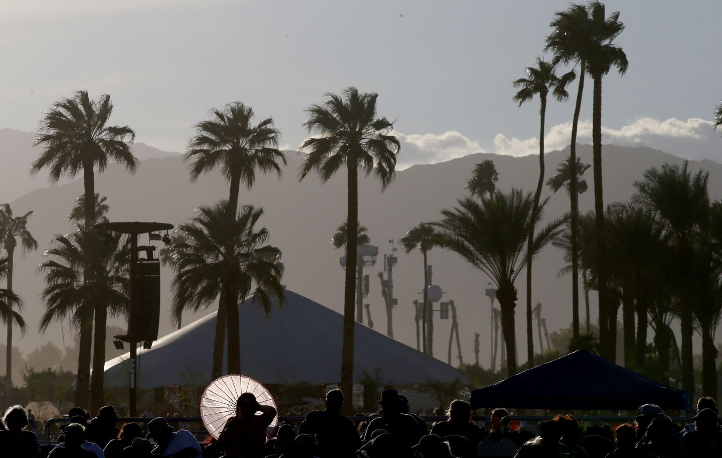A music fan seeks shade from the sun as it sets during the second weekend of Desert Trip in Indio.