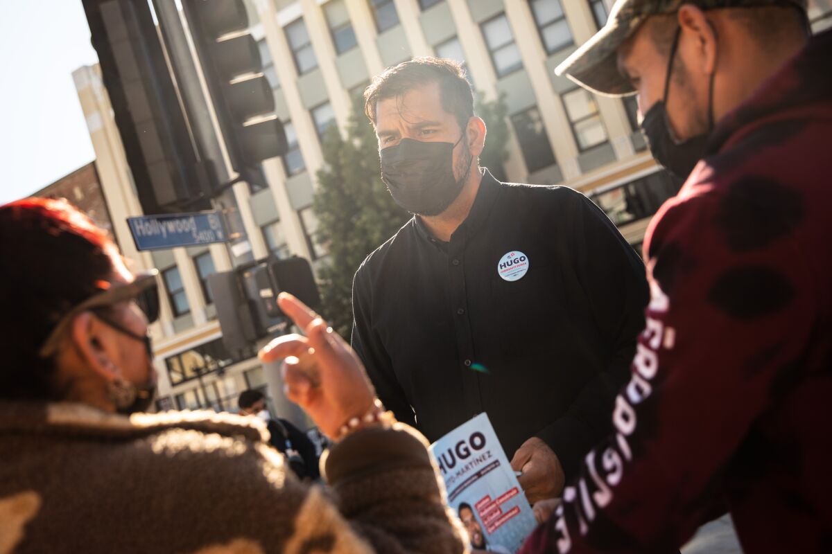 Hugo Soto-Martinez in a mask talking to two people on the street.