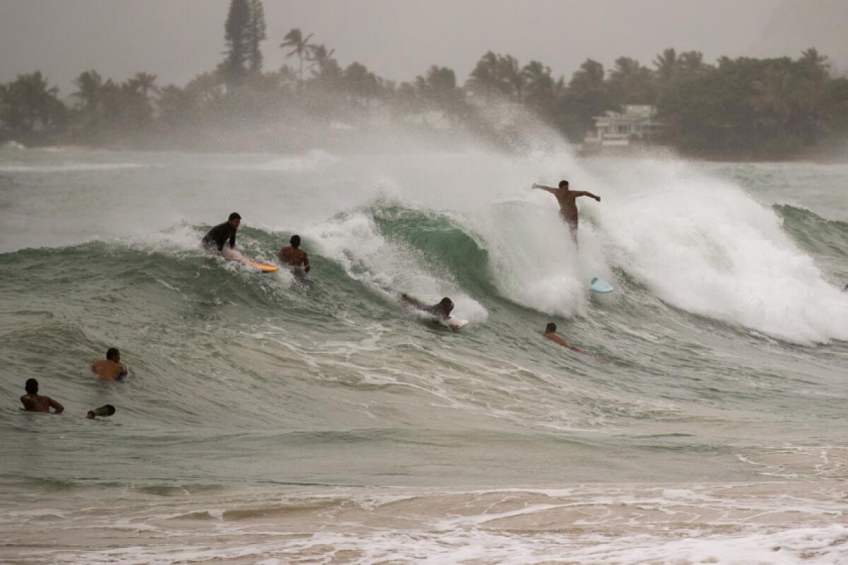 Surfers take on large waves generated by Hurricane Douglas on Sunday at Laie Beach Park on Oahu.