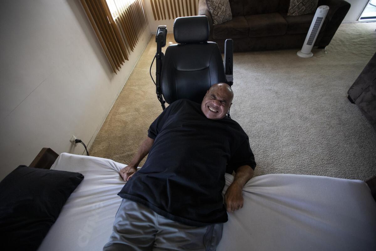 Bill Crawford pulls himself out of bed in his living room in Watts.