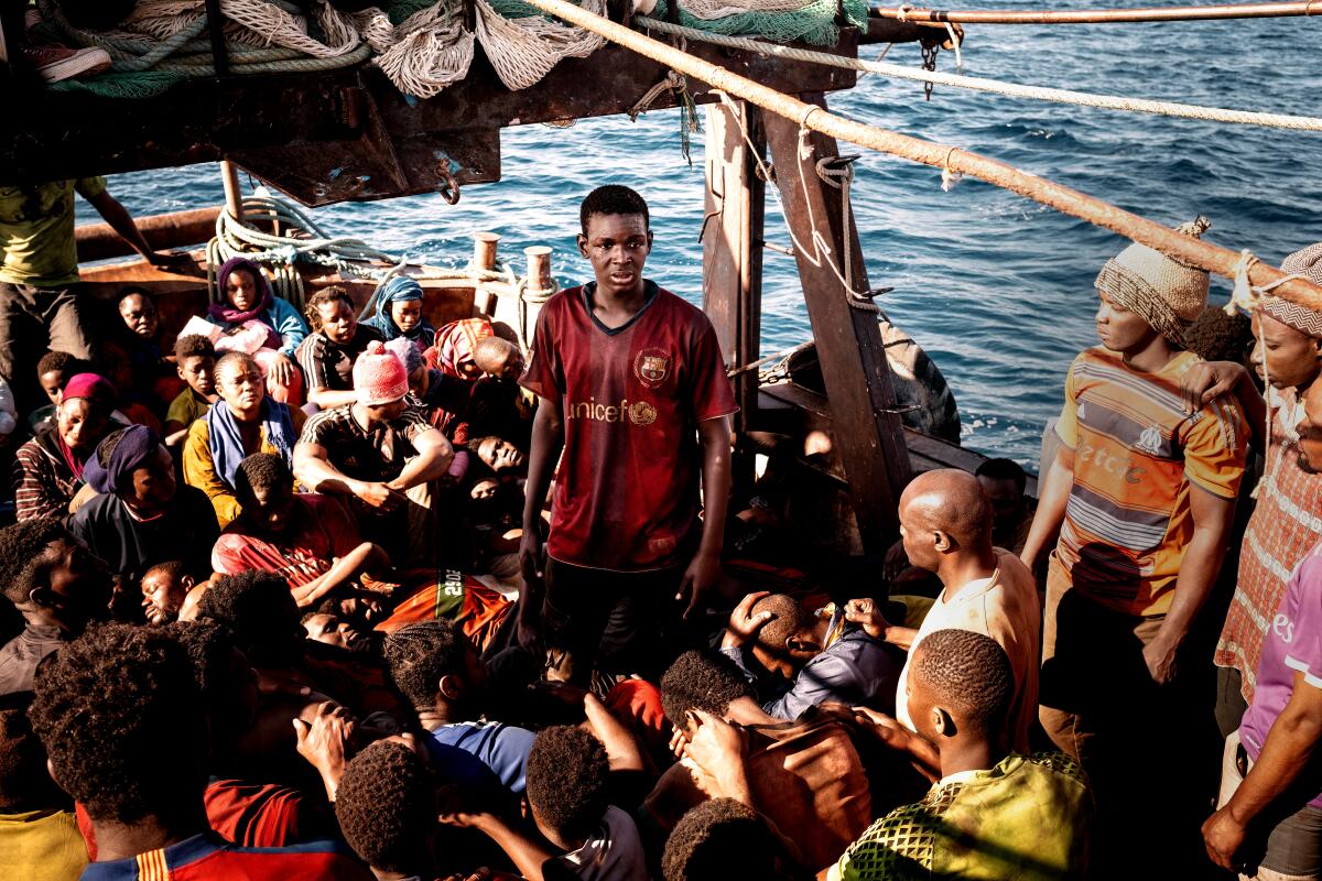 One young man stands amid a crowd of seated passengers crammed on a boat in "Io Capitano."
