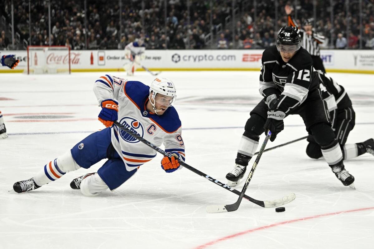 Edmonton Oilers' Connor McDavid falls as he tries to pass the puck while under pressure from Kings' Trevor Moore.