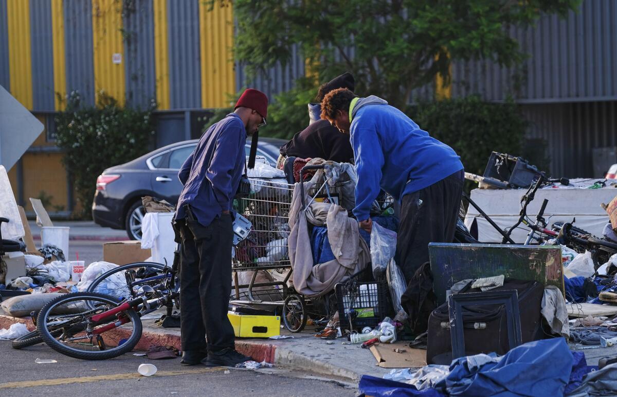 Homeless men sort through their belongings on a traffic island near downtown Los Angeles last month.