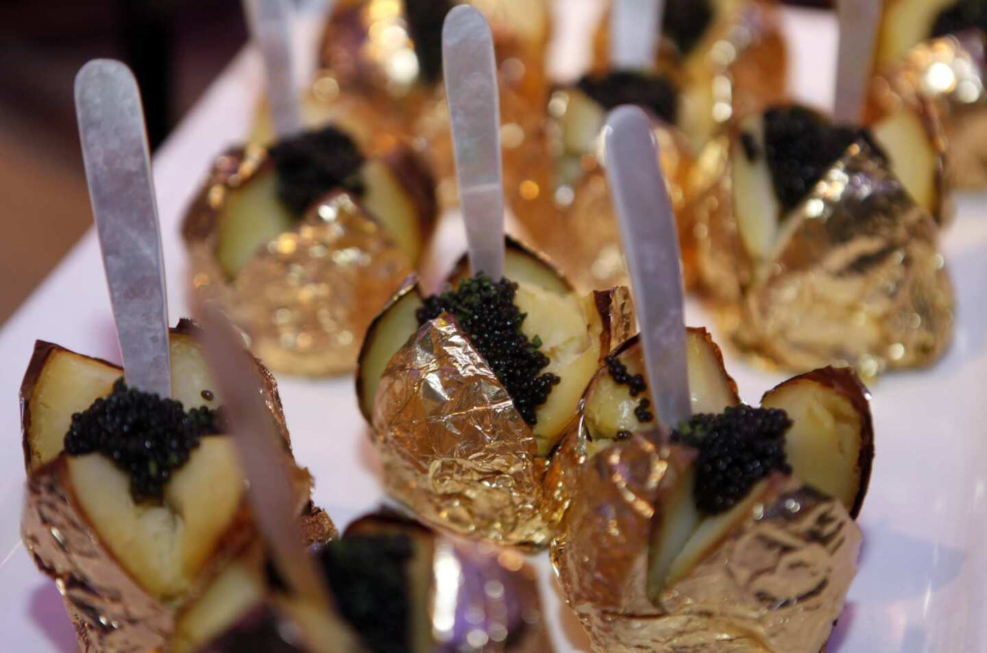 Gold-wrapped baked potatoes are garnished with caviar and crème fraiche.