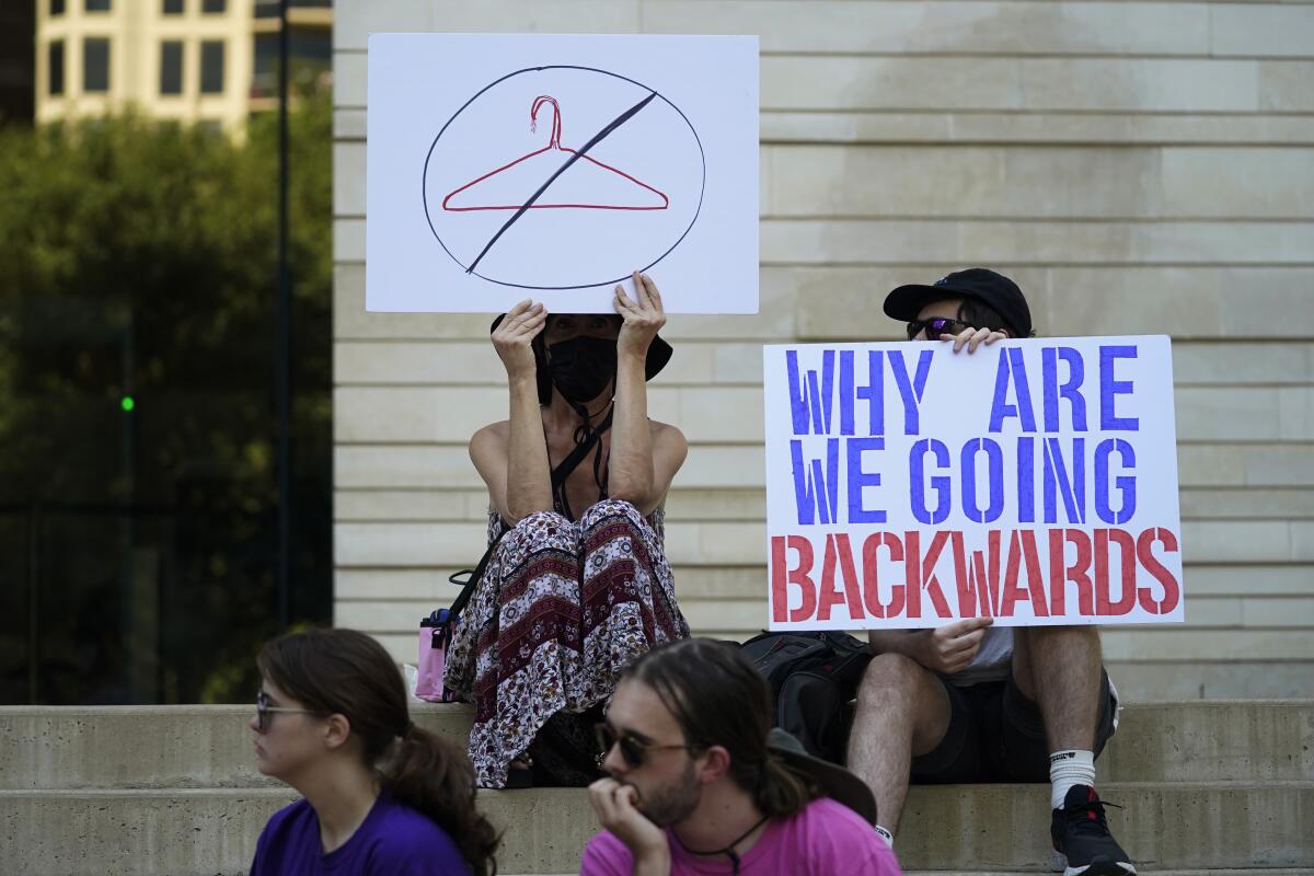 People sit on steps and hold up signs.