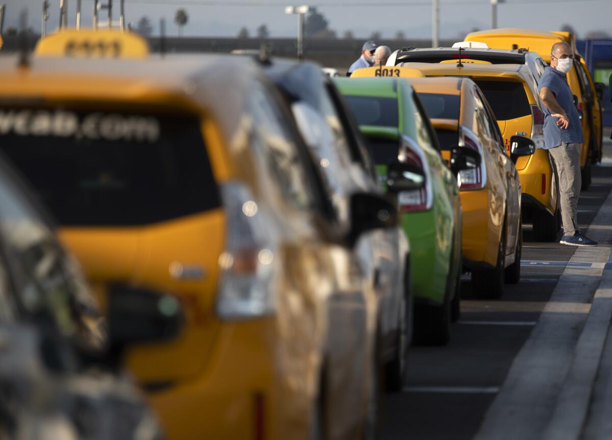 Taxi driver Ara Sahakyan stands next to a row of waiting taxis at LAX-it.