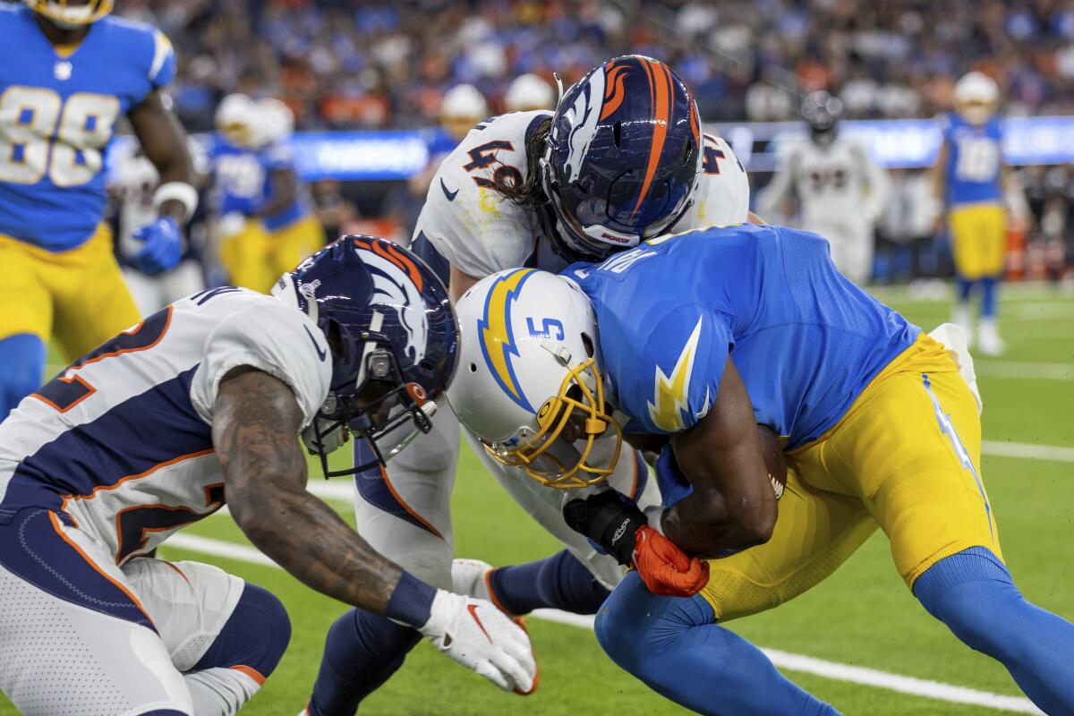 The Chargers' Joshua Palmer (5) runs after a catch and is about to make helmet-to-helmet contact as Broncos defenders pursue.