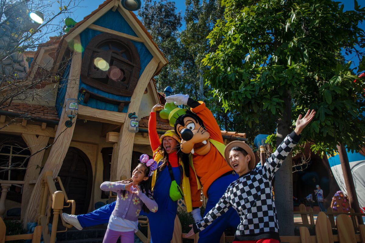 A family of three poses with the Disney character Goofy.
