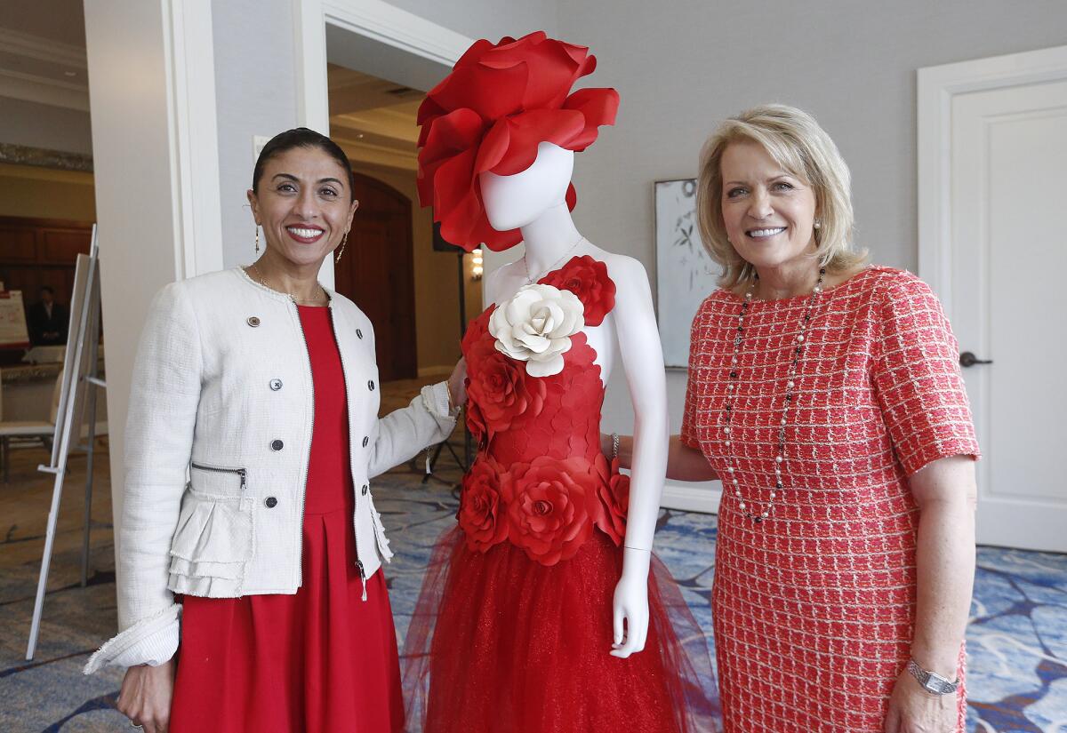 Dareen Khatib, board member, and event chair Melanie Graper, from left, stand with "the red dress."