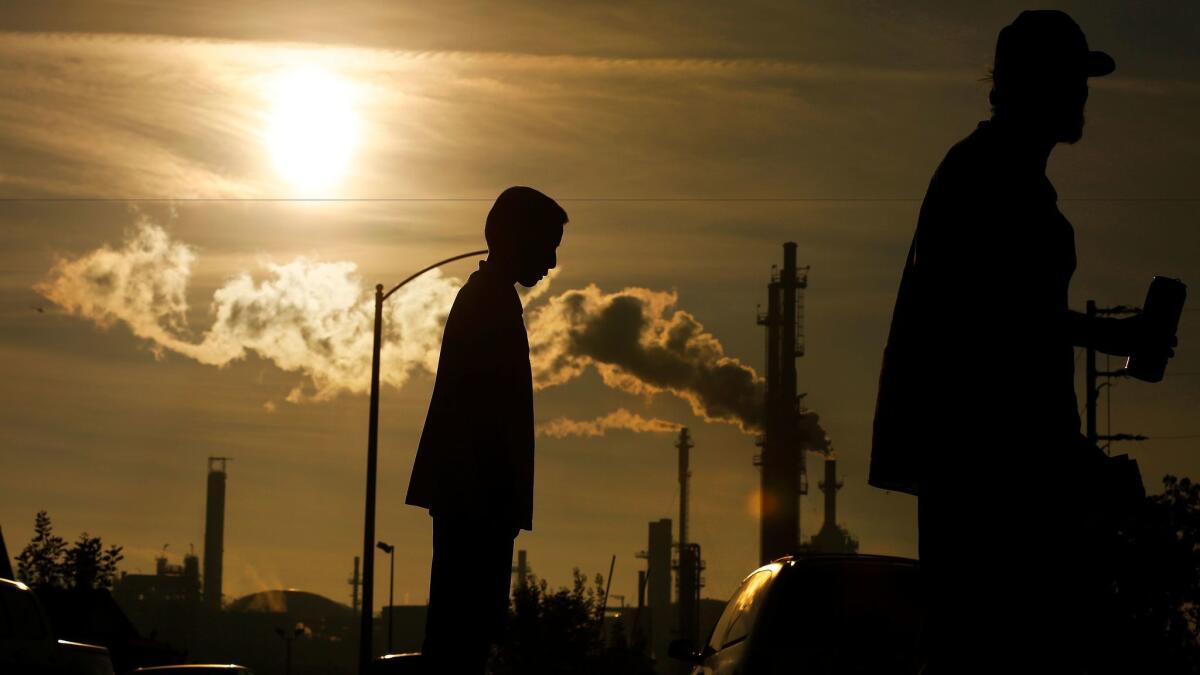 Jesse Ceja, left, and his grandfather Paulo Torres, 69, stand on Emden Street in Wilmington near their home adjacent to the Phillips 66 refinery.