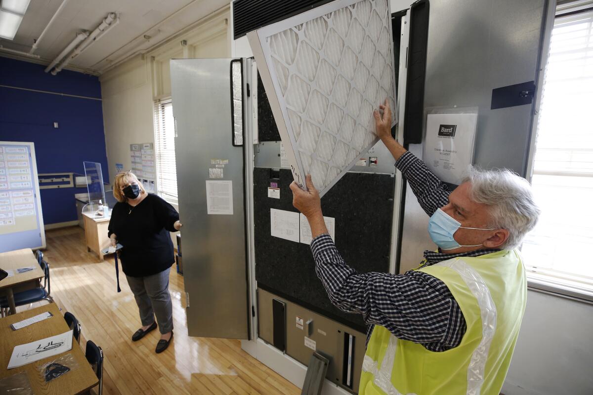 A project manager shows the air filtering system in L.A. district classroom. 