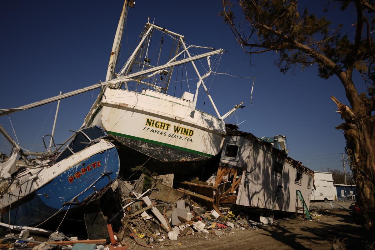 A boat called Night Wind and another named Popeye sit atop rubble and against the remains of an apartment building. 