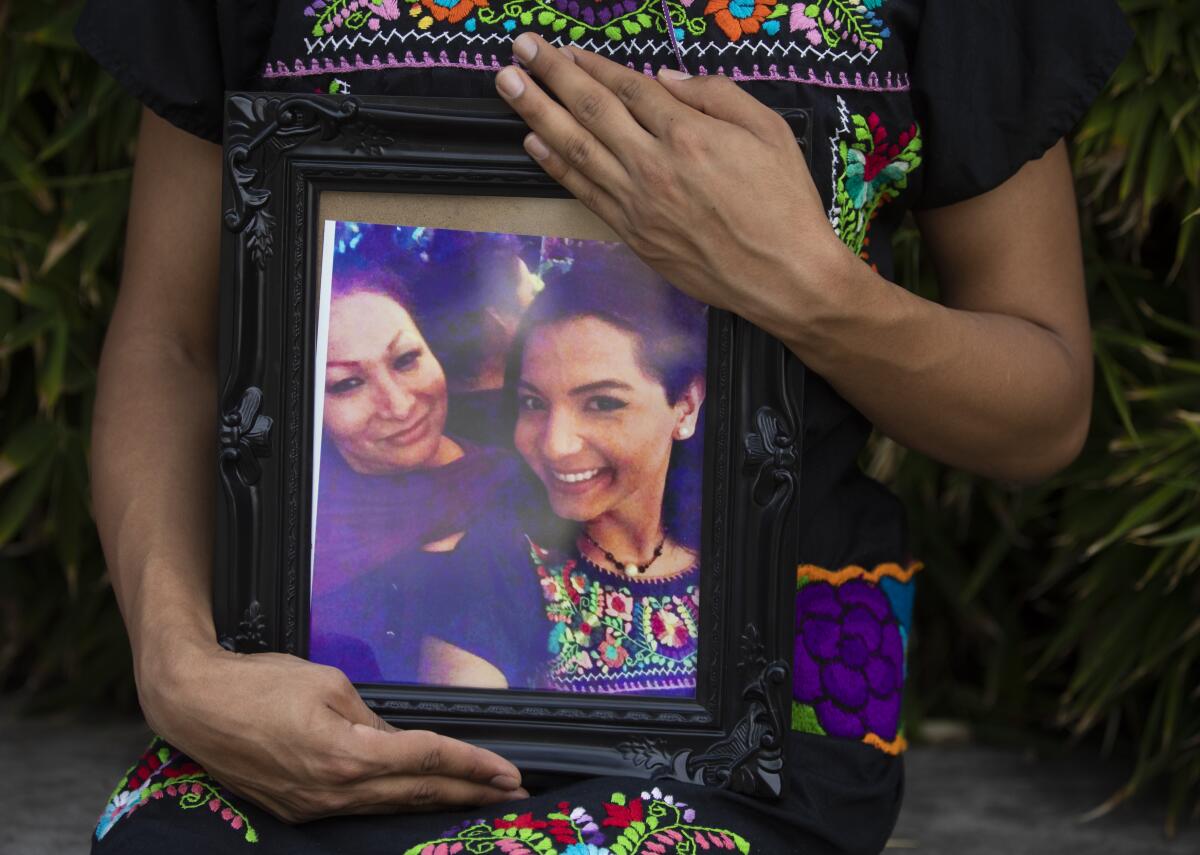 A portrait of Pink Moon Midnight Blue holding a photo of her friend Angela Martinez, left.