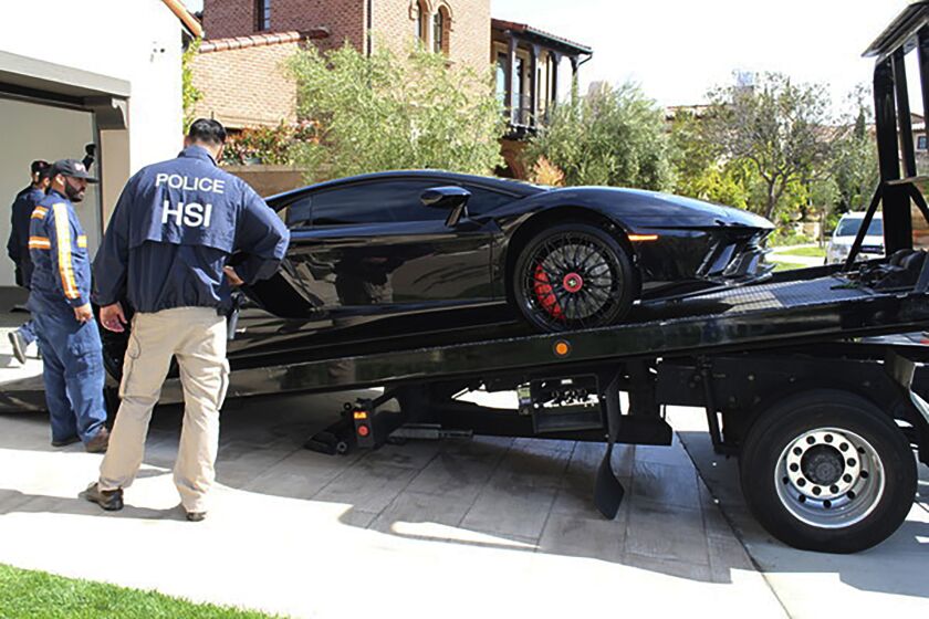 This photo provided by U.S. Immigration and Customs Enforcement shows special agents with HSI Los Angeles's El Camino Real Financial Crimes Task Force seize a Lamborghini from an Orange County businessman on Thursday, April 6, 2021, in Irvine, Calif. Mustafa Qadiri, 38, of Irvine, was named in a federal grand jury indictment and has pleaded not guilty to charges he obtained $5 million in federal coronavirus-relief loans for phony businesses and then used the money for lavish vacations and to buy a Ferrari, Bentley and Lamborghini, prosecutors said Monday, May 10. (U.S. Immigration and Customs Enforcement via AP)