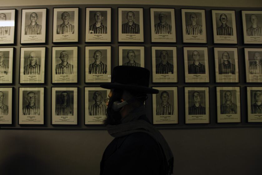 An orthodox Jew walks past the portraits of victims at the former Nazi German concentration and extermination camp Auschwitz-Birkenau in Oswiecim, Poland, Thursday, Jan. 26, 2023. Survivors of Auschwitz-Birkenau are gathering to commemorate the 78th anniversary of the liberation of the Nazi German death camp in the final months of World War II, amid horror that yet another war has shattered the peace in Europe. The camp was liberated by Soviet troops on Jan. 27, 1945. (AP Photo/Michal Dyjuk)