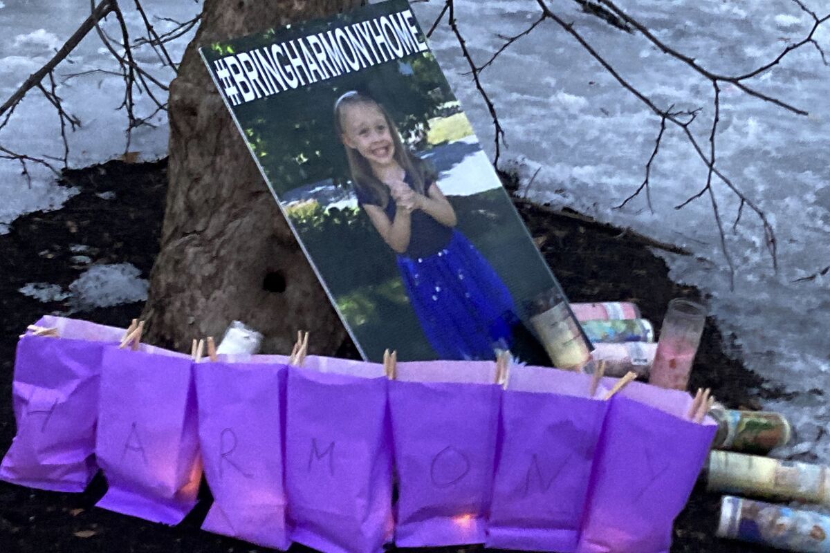 A poster of Harmony Montgomery, who has been missing since 2019, rests against a tree during a candlelight vigil, Feb. 12, 2022, at Bass Island Park, in Manchester, N.H. An independent state agency that represents children says the needs of a girl who authorities began looking for two years after she went missing were not prioritized by the state of Massachusetts. A report Wednesday, May 4, 2022 from the head of the Office of the Child Advocate said Harmony Montgomery, who was last seen in 2019 at age 5, suffered from "miscalculations of risk and unequal weight placed on parents' rights versus a child's wellbeing." (AP Photo/Kathy McCormack, File)