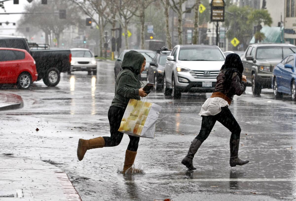 A couple of women dash across a flooded Brand Blvd. at California Ave. with the lunch from Panera Bread in Glendale on a rainy Friday, Feb. 28, 2014. The storm continues through the weekend.