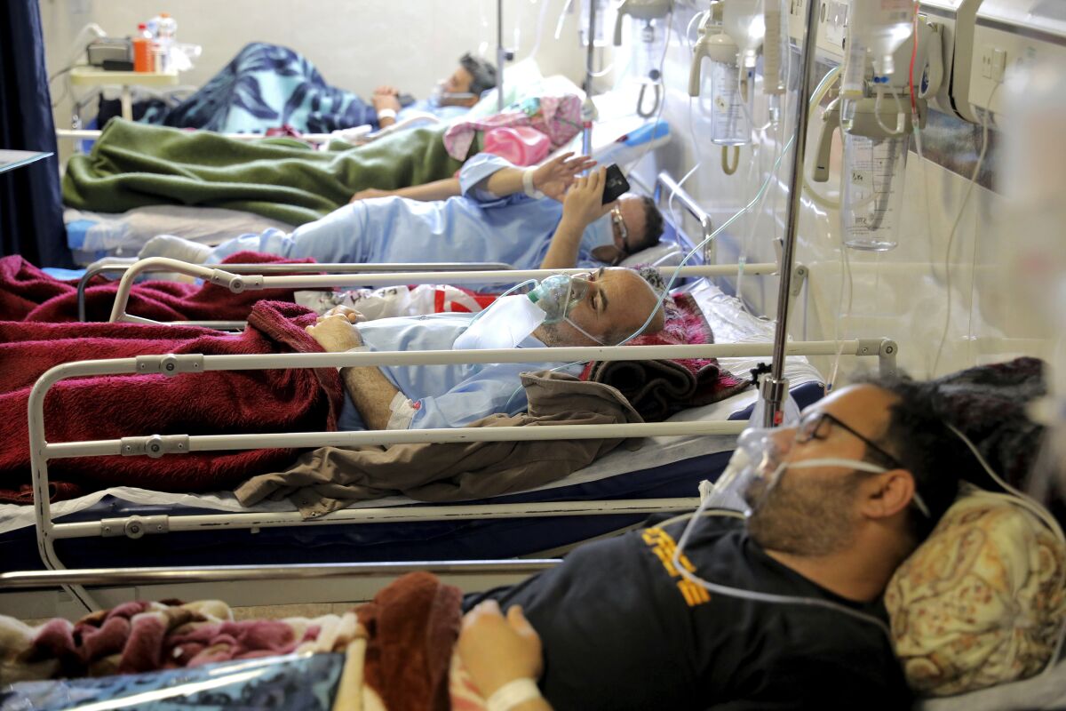 COVID-19 patients wearing oxygen masks lie in hospital beds