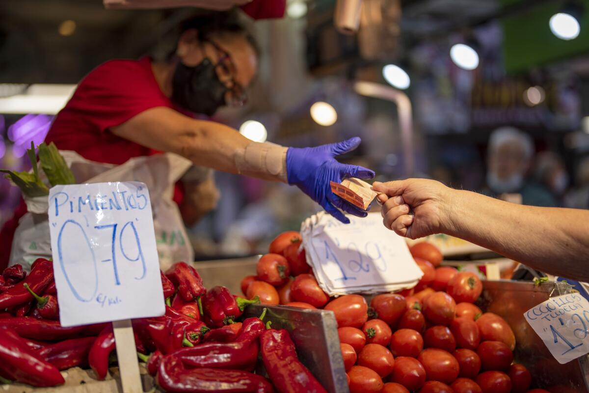 FILE - A customer pays for vegetables at the Maravillas market in Madrid, on May 12, 2022. Inflation figures for Europe will be released Friday, July 1, 2022, as Russia's war in Ukraine has worsened the worldwide surge in consumer prices. For months, inflation in the 19 countries that use the euro has risen at the fastest pace since record-keeping for the currency began. (AP Photo/Manu Fernandez, File)
