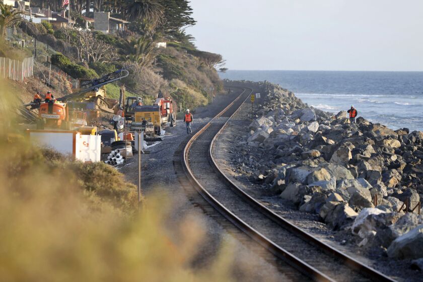 San Clemente, CA - November 28: South of San Clemente State Beach railroad and bluff repairs occur below the Cypress Cove development at upper left. At far left are workers repairing the bluff. Boulders have been placed between the tracks and the ocean. (Charlie Neuman / For The San Diego Union-Tribune)