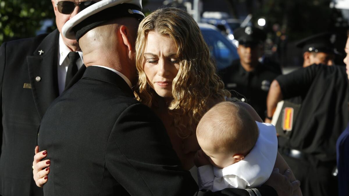 Danielle Wong holds her son, Colton, as she arrives for funeral services on June 16, 2017, at the Cathedral of Our Lady of the Angels for her husband, firefighter Kelly Wong.