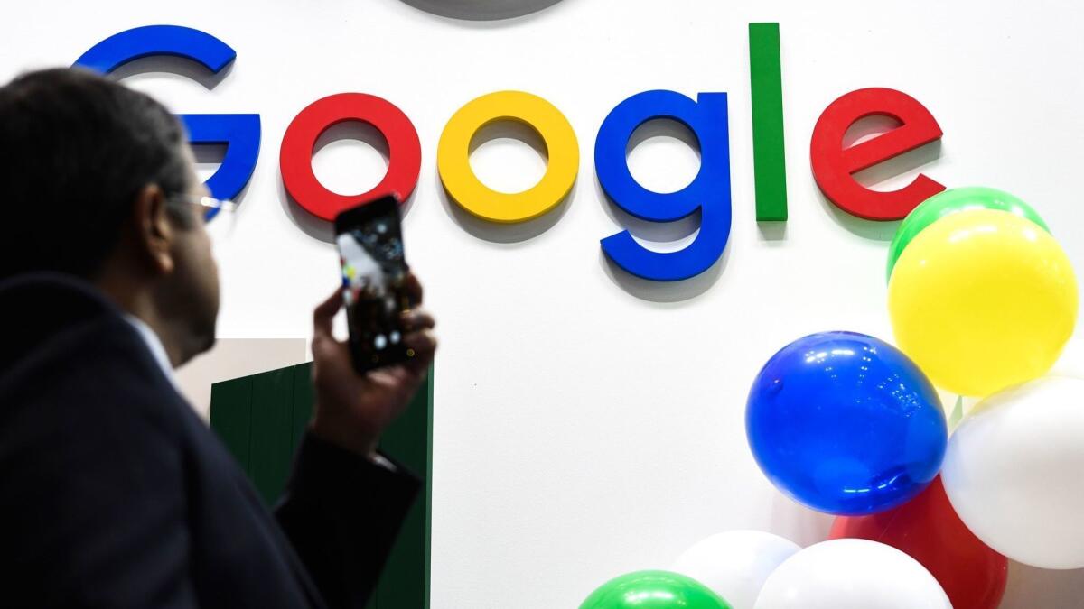 A man takes a picture of the Google logo at a Paris tech fair.