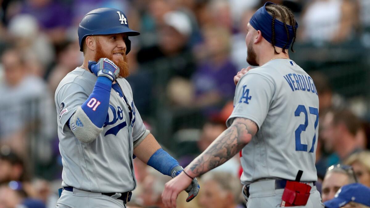The Dodgers' Justin Turner, left, is congratulated by teammate Alex Verdugo after hitting a solo home run in the fifth inning against the Colorado Rockies in Denver on Thursday.