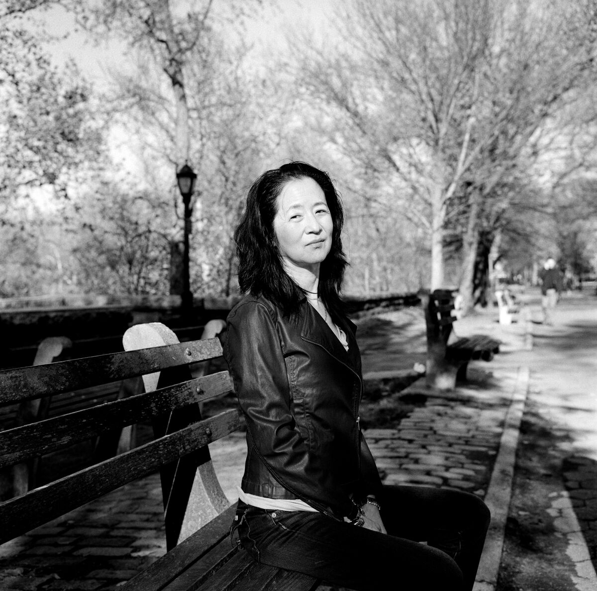 A black-and-white photo of a woman on a park bench