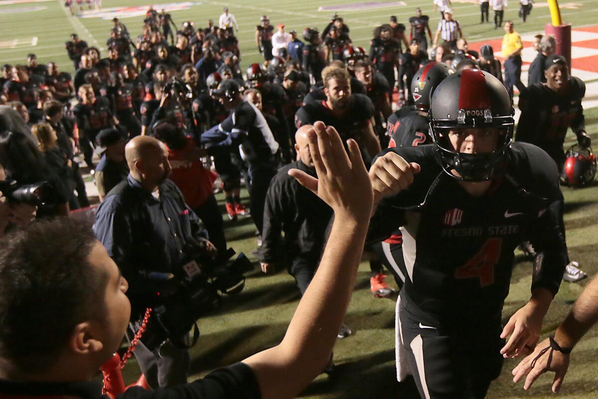 Fresno State quarterback Derek Carr high-fives a fan as he leaves the field at halftime against Nevada.