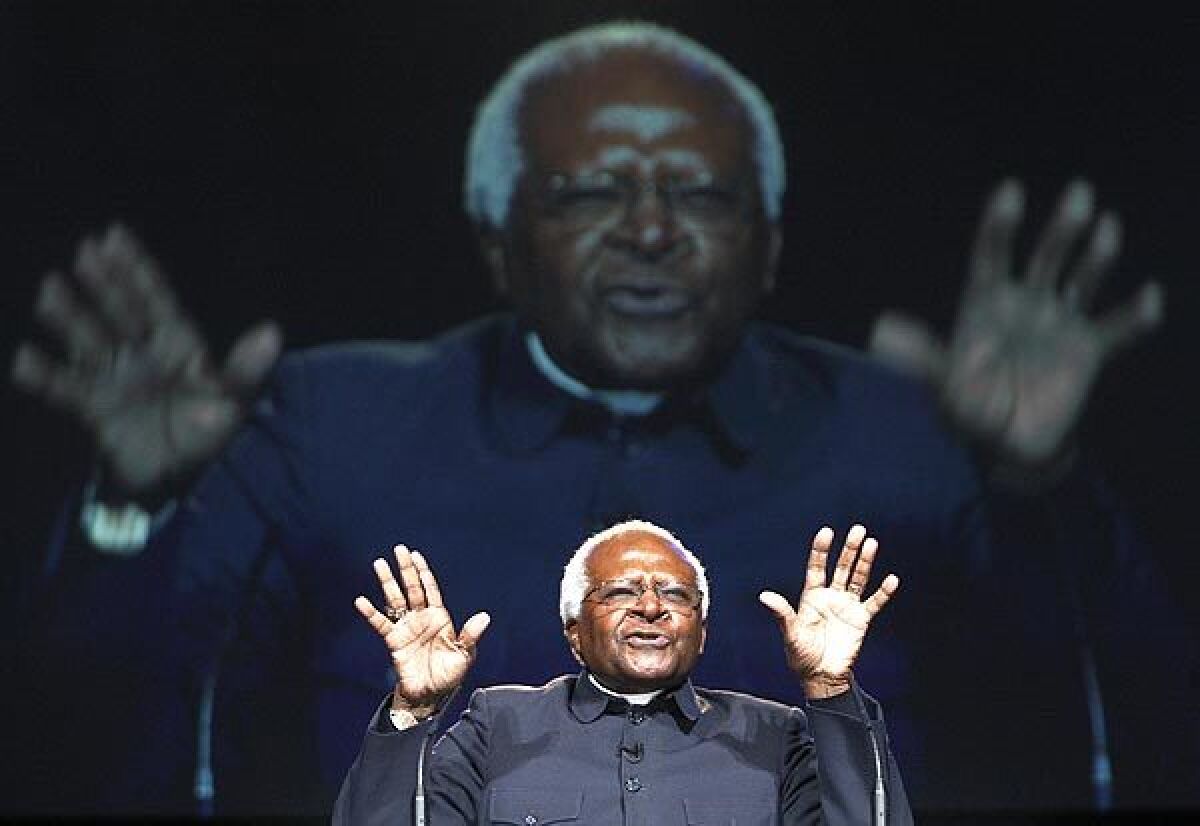 Desmond Tutu raises his hands as he speaks at an event.