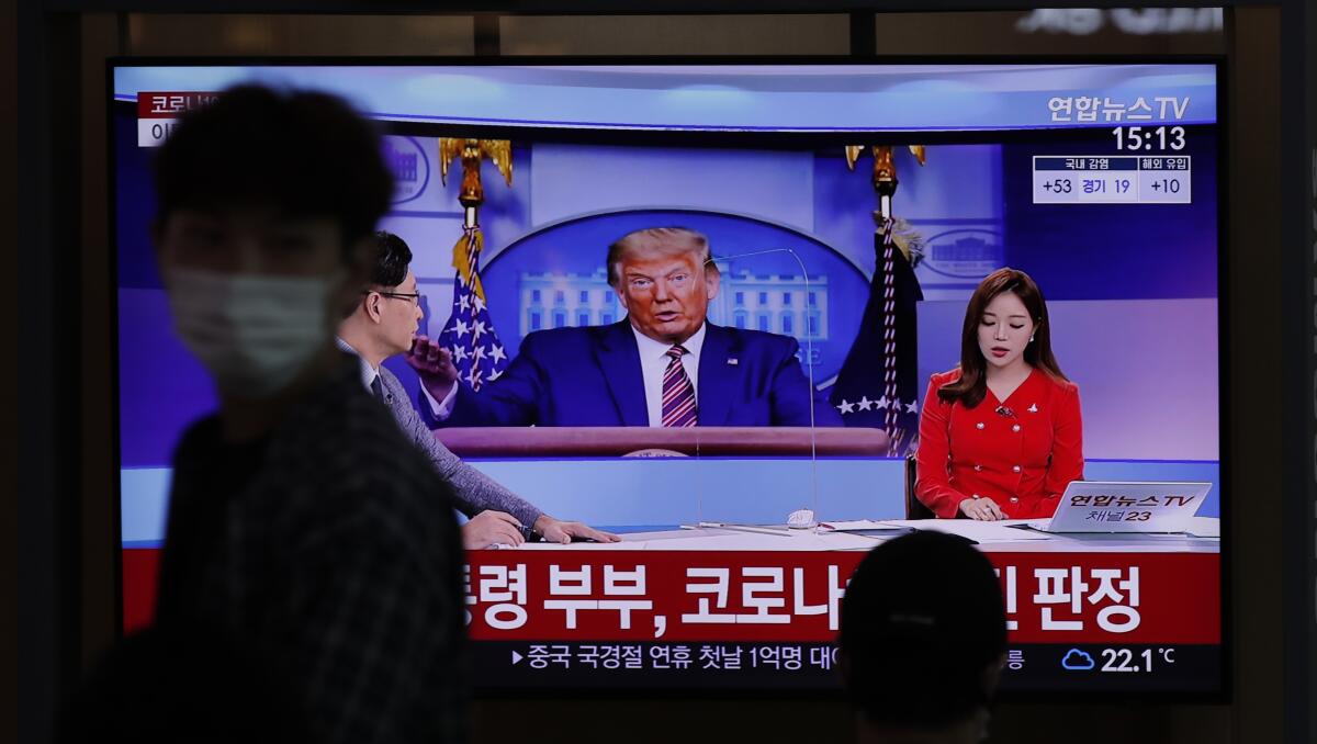 A commuter at the Seoul Railway Station walks past a TV screen featuring coverage of President Trump.