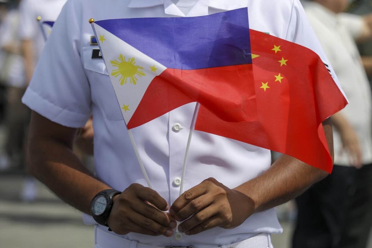 A Coast Guard member holds Chinese and Philippine flags.