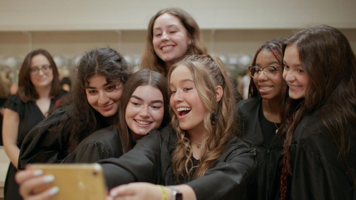 High-school girls wear black judges' robes.