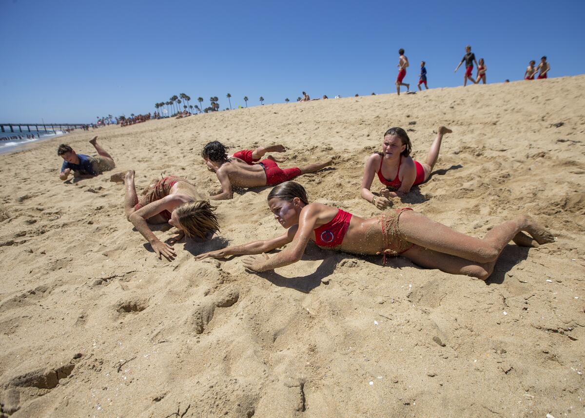 A group of Newport Beach Junior Lifeguards does log rolls.