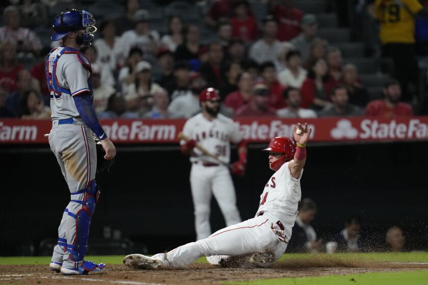 Los Angeles Angels' Logan O'Hoppe (14) scores after Eduardo Escobar grounded out during the fourth inning of the team's baseball game against the Texas Rangers in Anaheim, Calif., Tuesday, Sept. 26, 2023. Rangers catcher Jonah Heim is at left. (AP Photo/Ashley Landis)